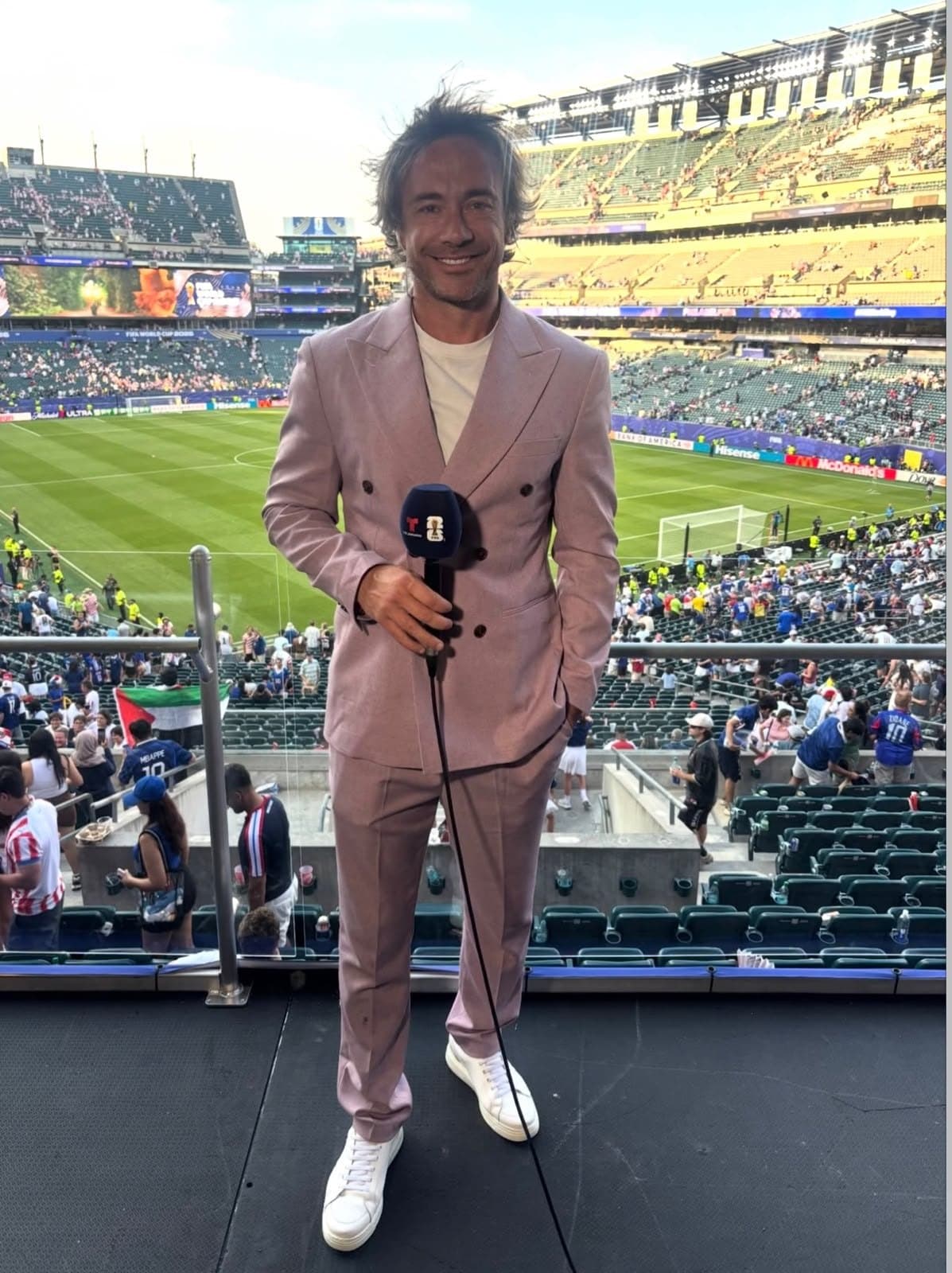Diego Lugano holding a Telemundo microphone in the stadium broadcast booth.